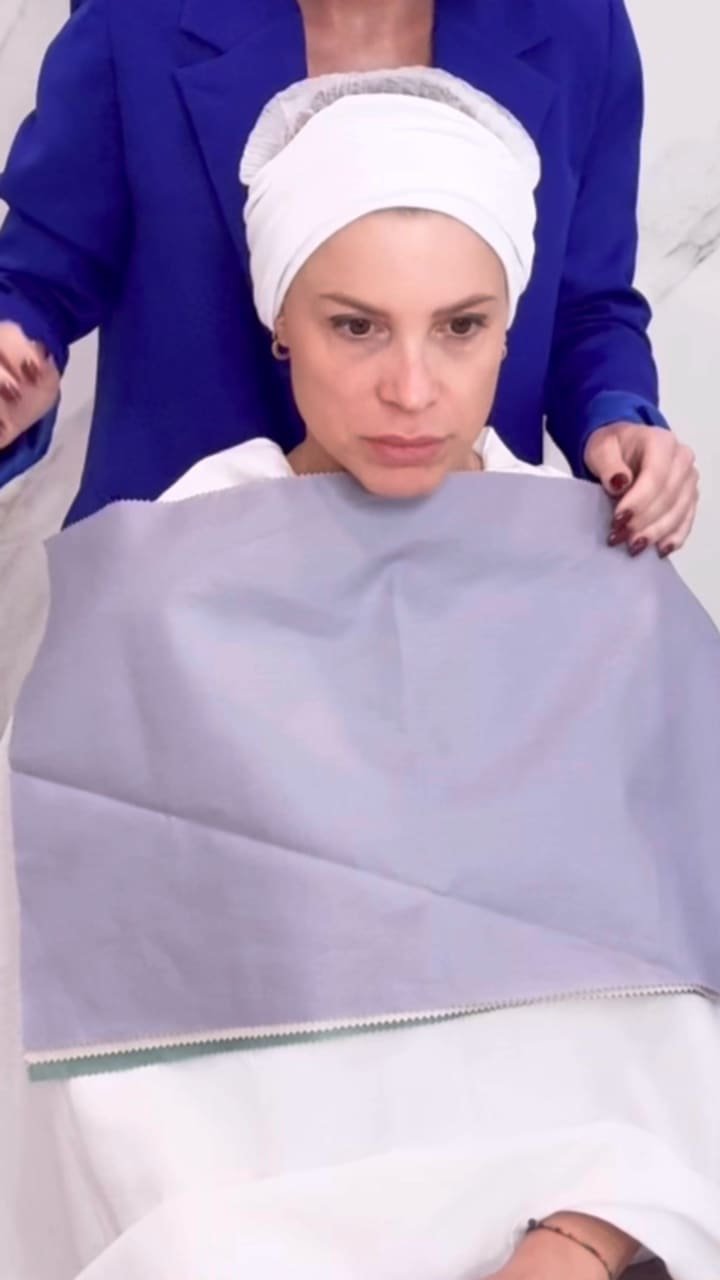 Primo piano di una cliente con un drappo lilla, le mani di Erica sulle spalle.